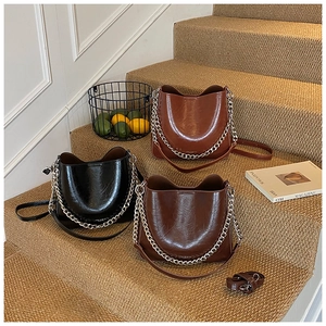Three-tier display of glossy pebble leather bucket bags in black, coffee, and brown red