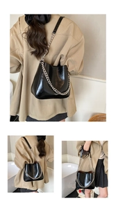 Detail of glossy black bucket bag featuring silver chunky chain and adjustable strap