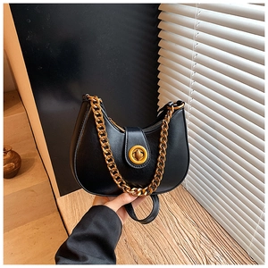 Dettaglio borsa hobo nera con catena dorata e chiusura con fibbia metallica rotonda