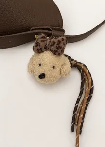 Detail of plush poodle bag charm with leopard bow on brown lychee leather tote