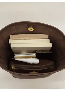 Interior detail of brown leather tote showing magnetic closure and large capacity storage