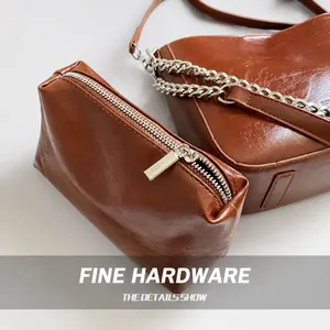 Detailed shot of brown wax leather bucket bag with silver chain and zipper texture