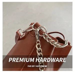 Detail of silver chain strap and durable metal clasp on brown oil-wax leather bucket bag