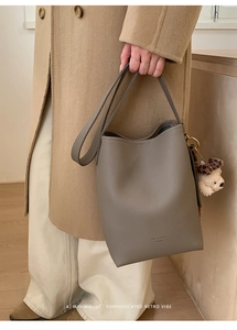 Close-up of gray litchi texture bucket bag with a cute leopard hat bear charm