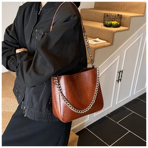 Detailed view of brown leather shoulder bag with stylish chunky silver chain decoration