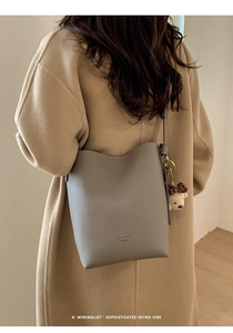 Macro view of grey pebble leather bucket bag with cute plush bear charm on strap