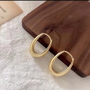 Chic polished gold oval hoop earrings on a rustic wood and linen background