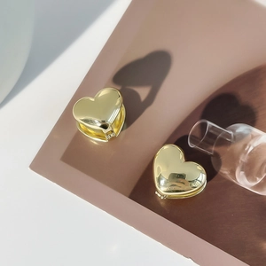 Macro detail of polished gold heart-shaped clip-on earrings with high-gloss metallic finish