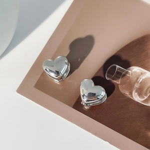 Detailed view of 3D metallic heart earrings with polished silver mirror finish on a display