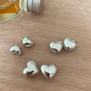 Detailed view of polished heart-shaped silver earrings on a rustic wood surface