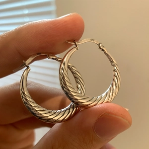 Hand holding vintage S925 sterling silver twisted cable hoop earrings with hinge clasp