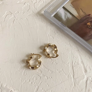 Vintage gold wavy pleated hoop earrings in 925 sterling silver on artistic display