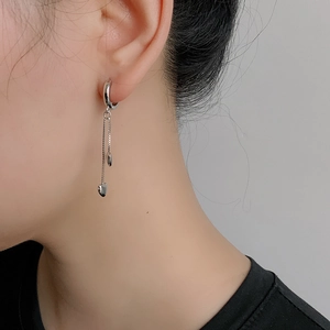 Gros plan de boucles d'oreilles cœur à pampilles en argent S925 au fini poli brillant
