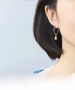 Gros plan d'une créole minimaliste en argent S925 avec pendentif goutte d'eau sur un modèle