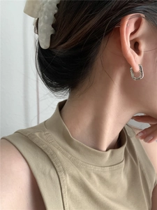 Close-up of vintage silver rectangle earrings and marble claw clip worn by a model