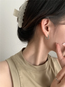 Close-up of vintage U-shaped S925 silver earrings with detailed relief engraving on a model