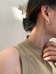 Close-up of vintage S925 silver U-shaped earrings with intricate black engraved patterns