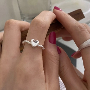 Detail of S925 silver twist knot ring with a 3D heart on a model's index finger
