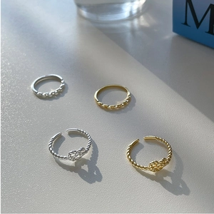 Set of four minimalist silver and gold twist knot heart rings displayed on a table