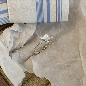 Macro shot of S925 silver twist ring with a polished heart detail on white paper