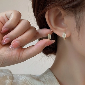 Gros plan de boucles d'oreilles feuille d'or avec micro-pave de zircone sur le lobe
