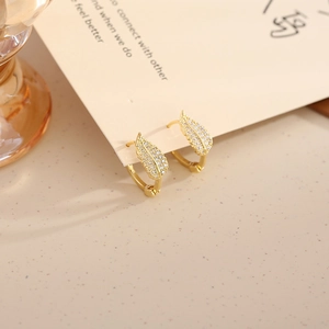 Détail macro de boucles d'oreilles feuille dorée avec micro-pavage de zircons cubiques