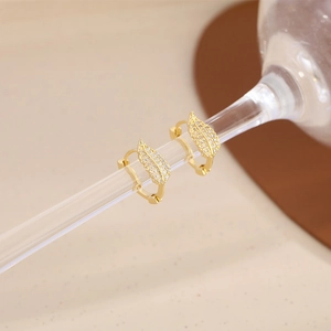 Gros plan de boucles d'oreilles feuilles dorées avec zircones micro-pavées sur verre