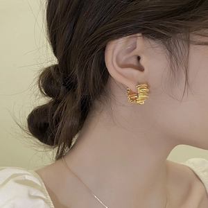 Détail macro de boucles d'oreilles dorées plissées irrégulières avec texture riche