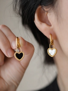 Vue détaillée des boucles d'oreilles cadenas cœur avec incrustations nacre noire et blanche