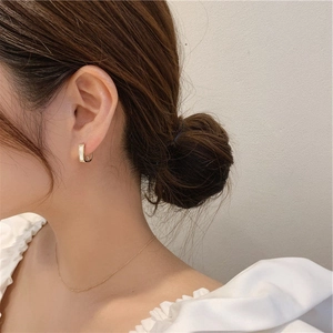 Minimalist gold U-shaped hoop earrings with shell inlay worn by model in warm lighting
