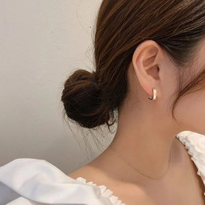 Close-up of elegant gold square earrings with white mother of pearl inlay on model