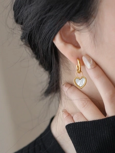 Boucles d'oreilles cœur vintage en or avec nacre blanche portées par un mannequin