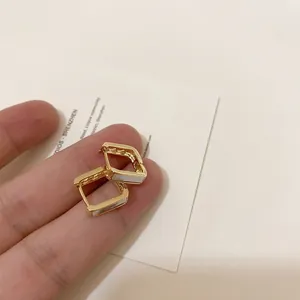 Detail of gold geometric hoop earrings with white mother of pearl inlay and side mesh texture