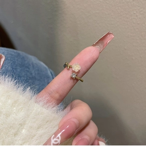 Detail of gold open ring featuring a white camellia flower and sparkling zircon accent