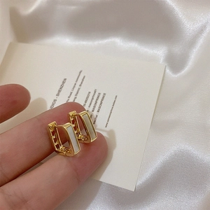 Macro shot of gold geometric earrings with white mother-of-pearl inlay detail