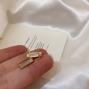Detail of square gold hoop earrings featuring elegant white mother of pearl inlay