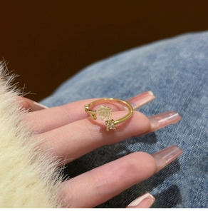 Detailed view of a gold open ring featuring a clear resin camellia and micro-set zircon