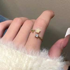 Detail of gold open ring with camellia flower and square zircon on hand