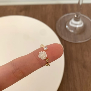 Close-up of white camellia open ring with sparkling zircon and gold-plated finish