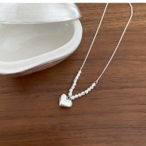 Detail of silver heart pendant and textured beads on an S925 sterling silver chain