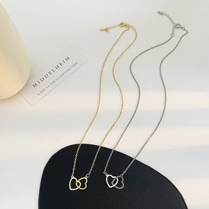 Detail of interlocking double heart necklaces in gold and silver with polished mirror finish