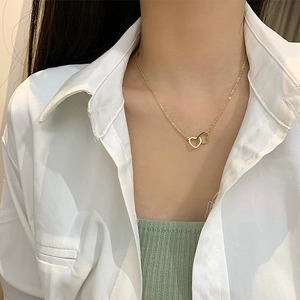 Close-up of golden interlocking double heart necklace on model with elegant style