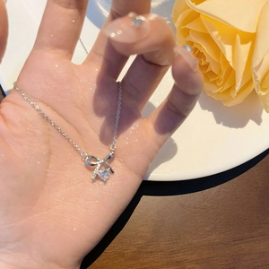 S925 silver bow necklace with heart-shaped zircon pendant displayed on hand with roses