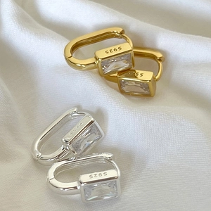 Macro shot of silver and gold U-shaped earrings with rectangular cubic zirconia
