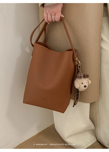 Detailed macro view of the brown bucket bag featuring a cute teddy bear charm