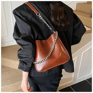 Caramel brown bucket bag with chunky silver chain and adjustable strap shown on model