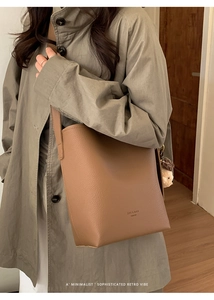 Close-up of brown pebbled leather bucket bag with cute plush bear charm on strap