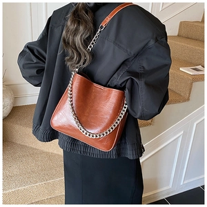 Detail of vintage brown oil wax leather bucket bag with silver chain and long strap
