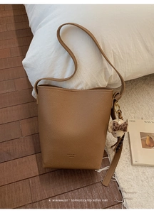 Detail of brown litchi leather bucket bag featuring a plush bear and leopard bow