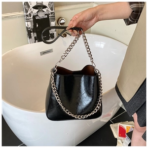 Detail of glossy black patent leather bucket bag with silver metal chunky chain strap